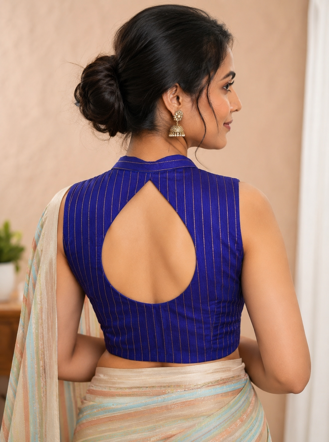Woman wearing a blue blouse with a cut-out design on a beige background