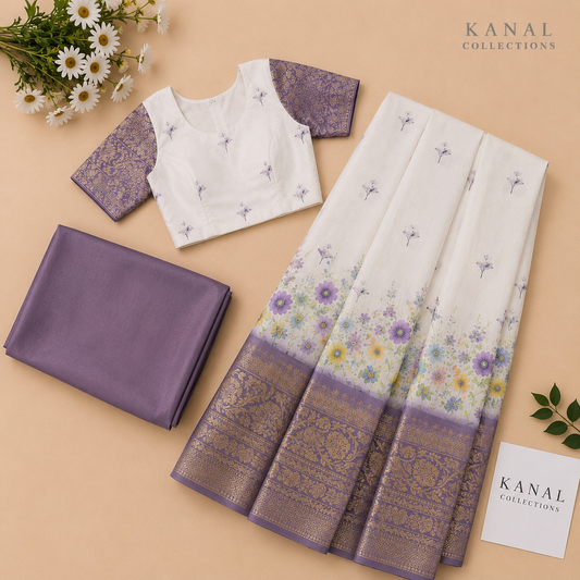 A traditional Indian ethnic wear set by Kanal Collections, featuring a white silk saree with purple floral patterns and a metallic gold border, paired with a white and purple embroidered blouse and a folded purple dupatta, arranged on a beige background with decorative daisies. Available from Kanal Collections Brisbane Australia. Ideal  Kerala outfit/ Dhavani/ half saree for your Onam celebration 