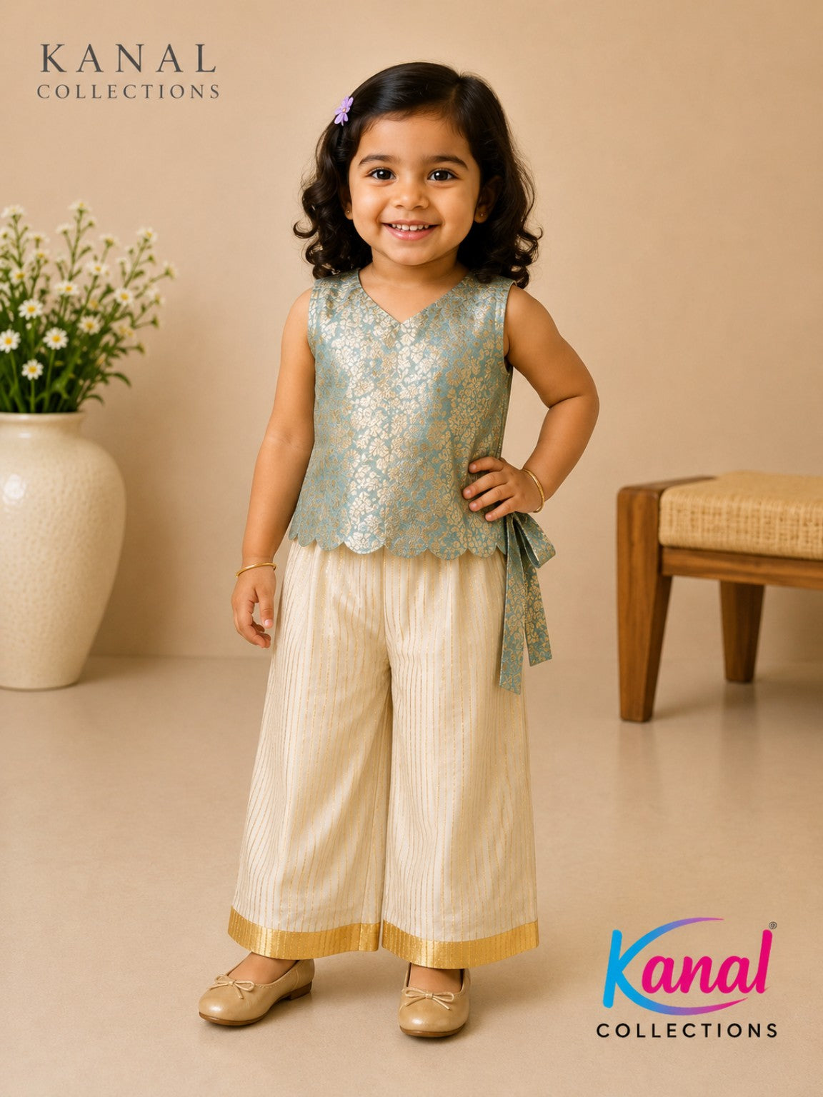 A young girl modeling a two-piece traditional outfit from Kanal Collections. The outfit features a sleeveless light blue-green lace top with a matching tie belt and cream-colored pleated pants with gold trim, set against a warm beige background with a wooden stool and a vase of flowers.