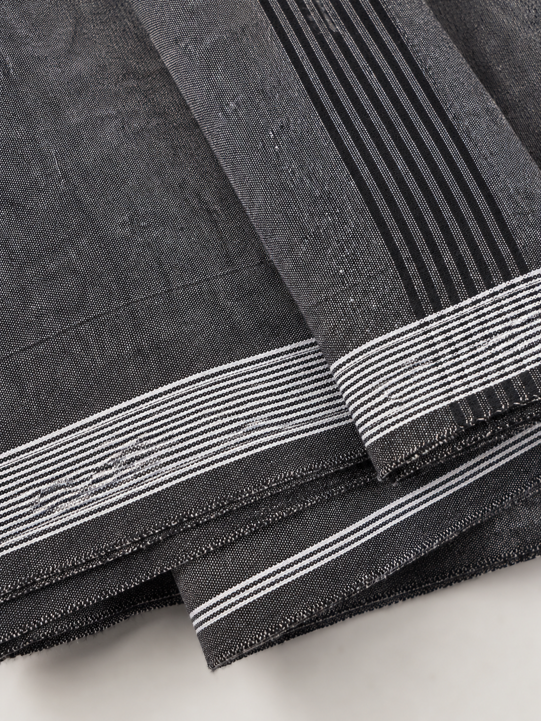 Close-up of black fabric with white stripes on a light gray background